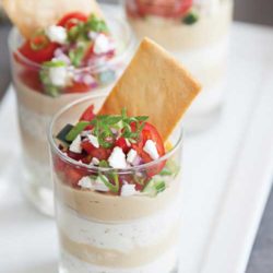 Start your game day crowd off with a 7-layer hummus dip, the perfect blend of veggies and cheese!