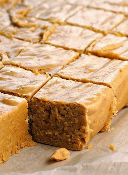 A wax paper lined tray covered with Pumpkin Pie Fudge cut into squares.