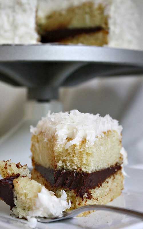 Recipe for Coconut Layer Cake with Chocolate Ganache Filling - If you like chocolate and coconut together, you’re going love this cake topped with Swiss meringue buttercream and coconut flakes!