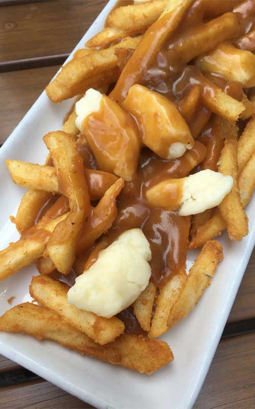 French Fries with Gravy and Cheese Curds - A savory mound of french-fried potatoes topped with beef gravy and fresh cheese curds. This Traditional Canadian Poutine is one the ultimate late-night snacks.